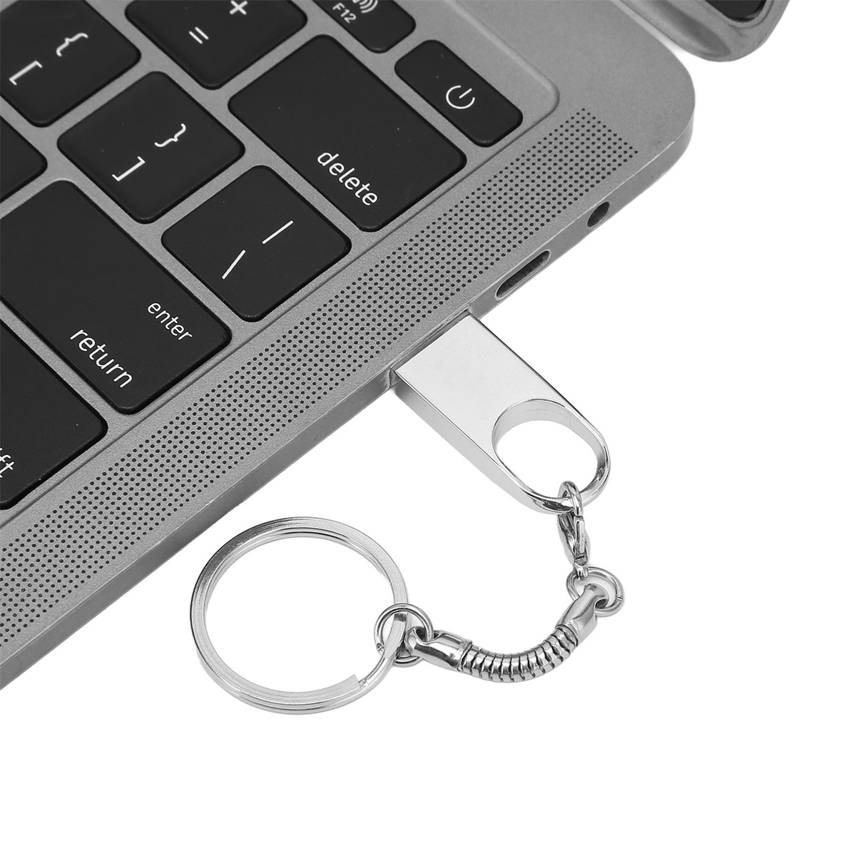 Ein silberner USB-Stick mit einem Schlüsselring, der mit einem Laptop verbunden ist.