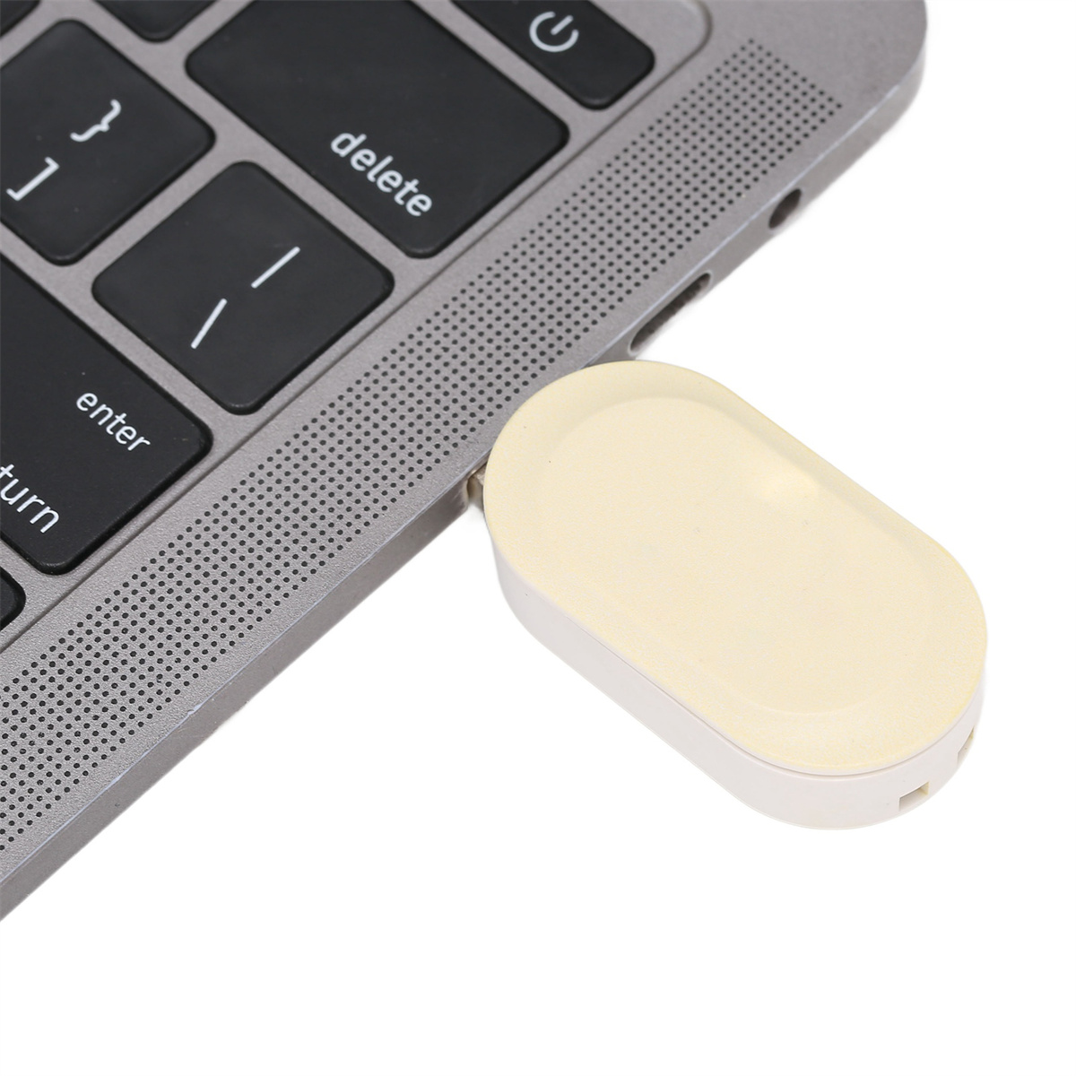 Ein kleiner, länglicher, cremefarbener USB-Stick, der an einen Laptop angeschlossen ist.