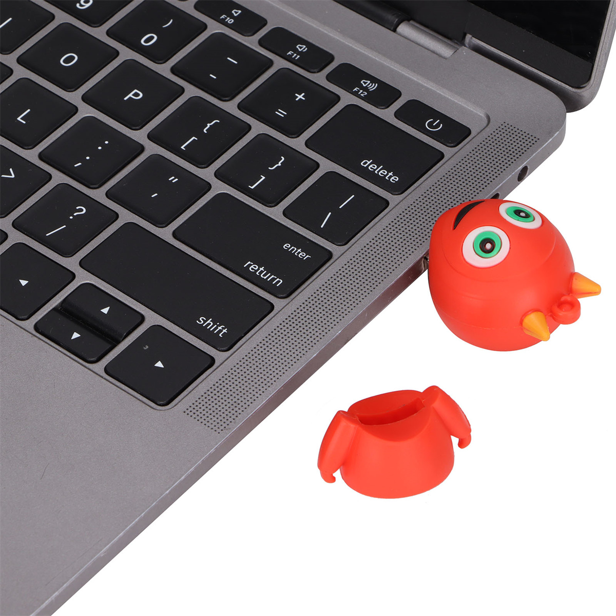Laptop-Tastatur mit rotem Spielzeugvogel und getrenntem Kopf. Weißer Hintergrund.