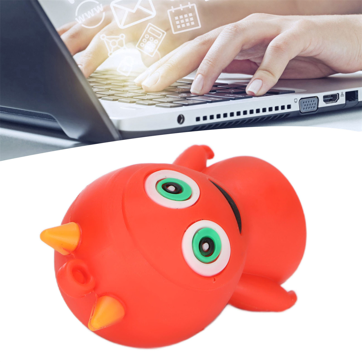 Eine Person, die einen Laptop über einem cartoonartigen roten Monstertoy mit grünen Augen und orangefarbenen Hörnern benutzt.