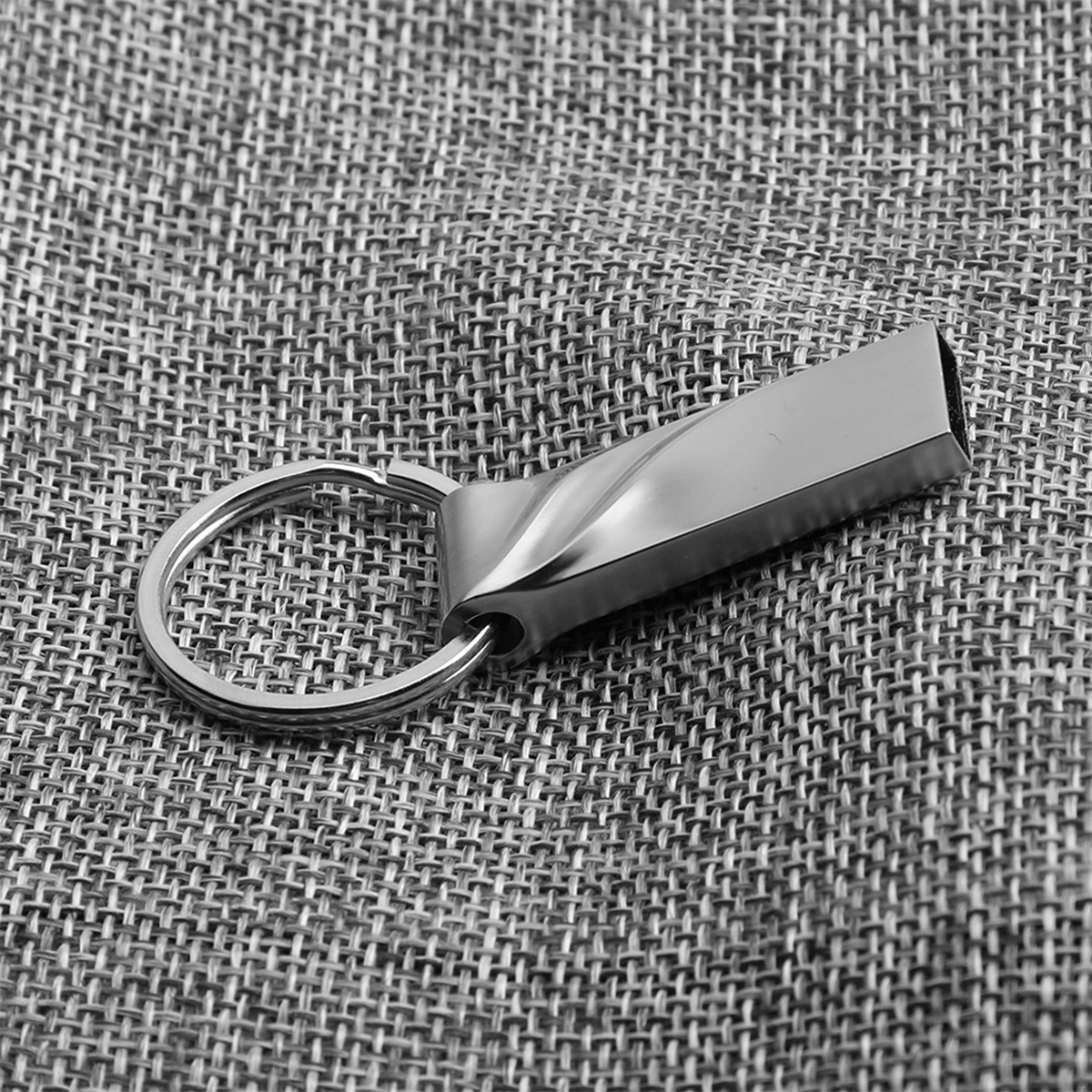 Silberner USB-Stick mit Schlüsselring auf grauem Untergrund.
