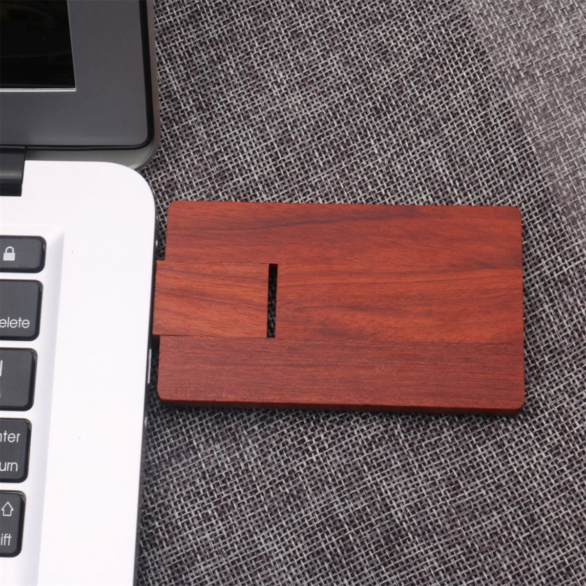 Holz-USB-Laufwerk neben einem Laptop. Das Laufwerk ist rechteckig und braun. Der Laptop ist weiß.