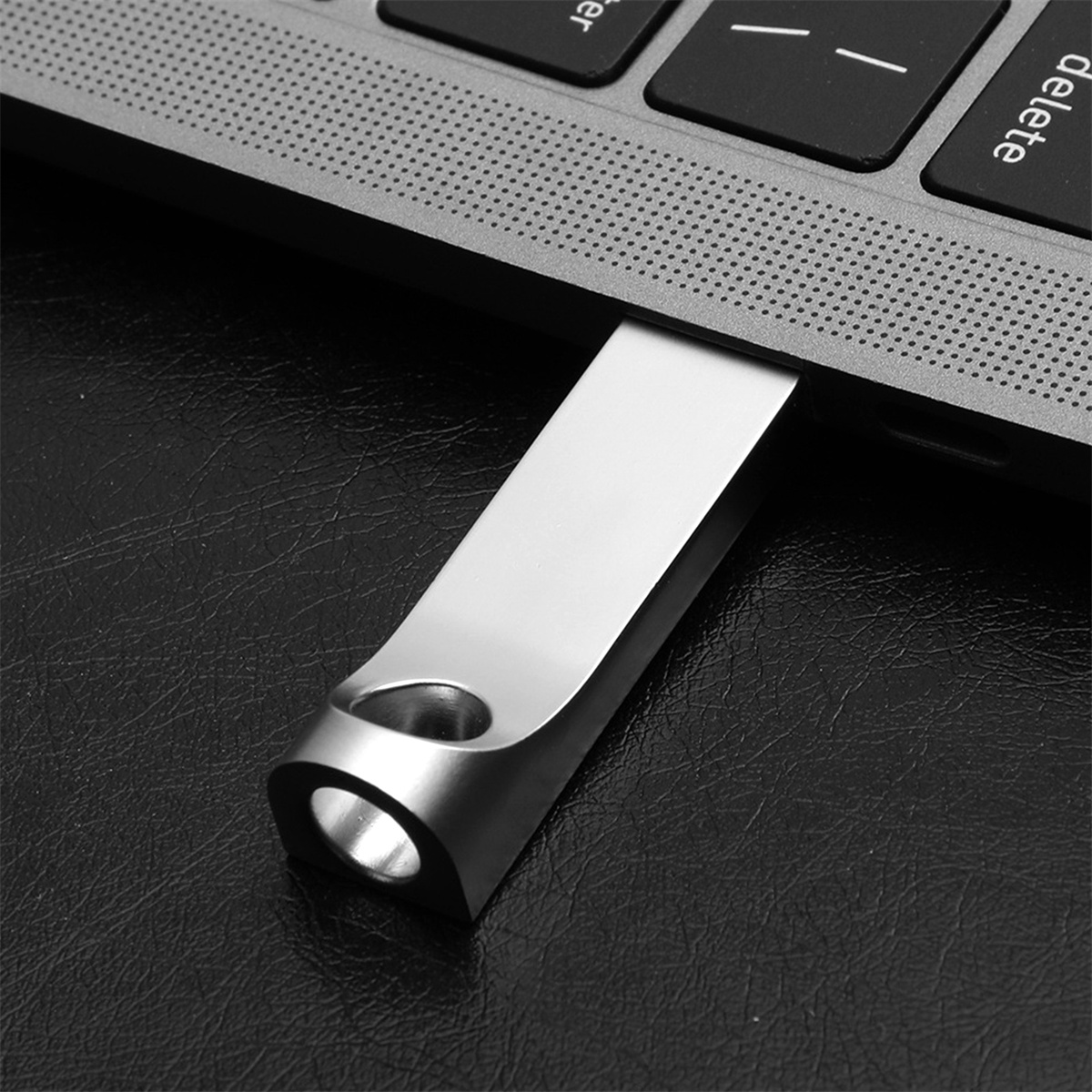 Silberner USB-Stick, der in einen Laptop eingesteckt ist, Nahaufnahme der Tastatur.