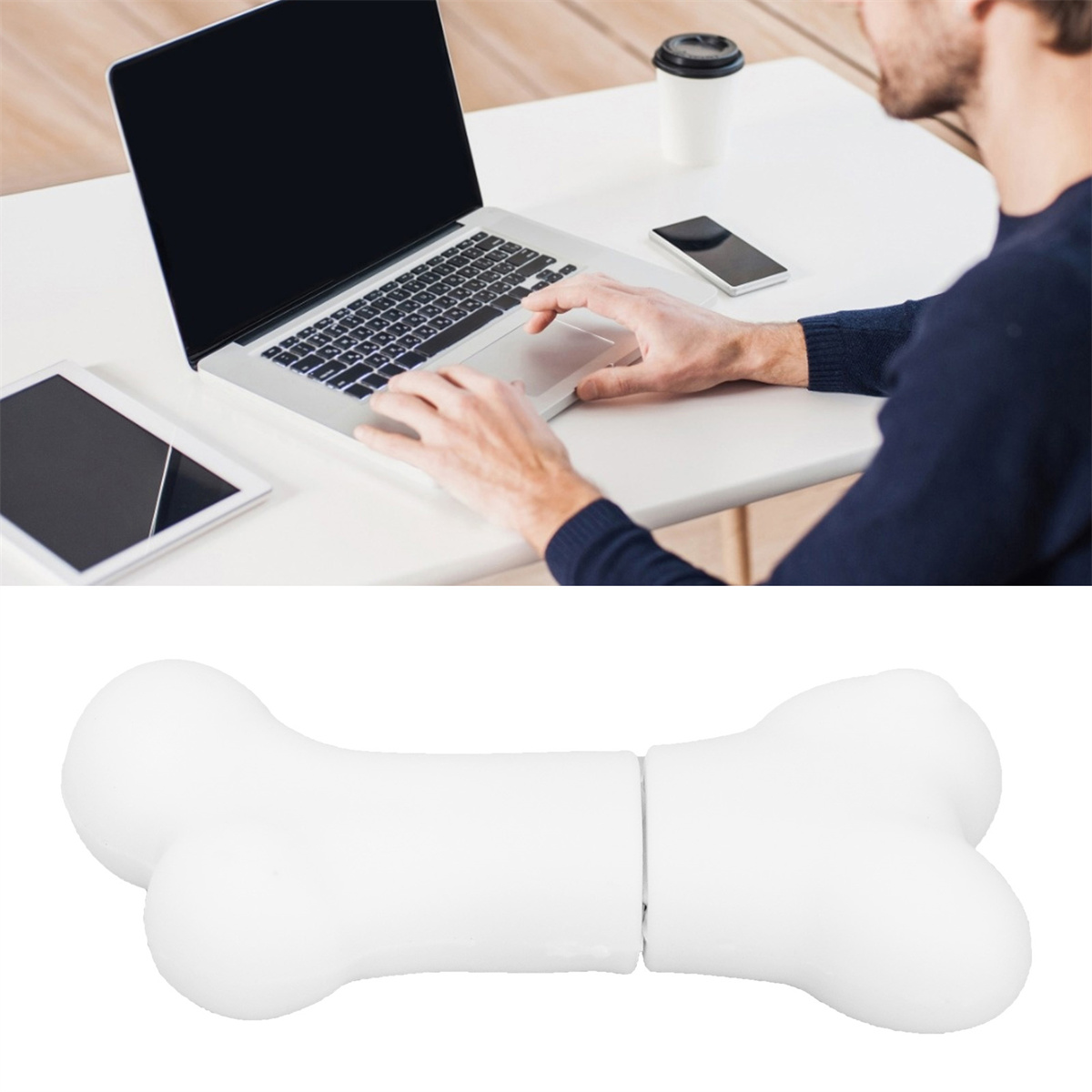 Mann benutzt Laptop auf weißem Schreibtisch, mit Tablet und Kaffeetasse. Knochenförmiger USB-Stick darunter.