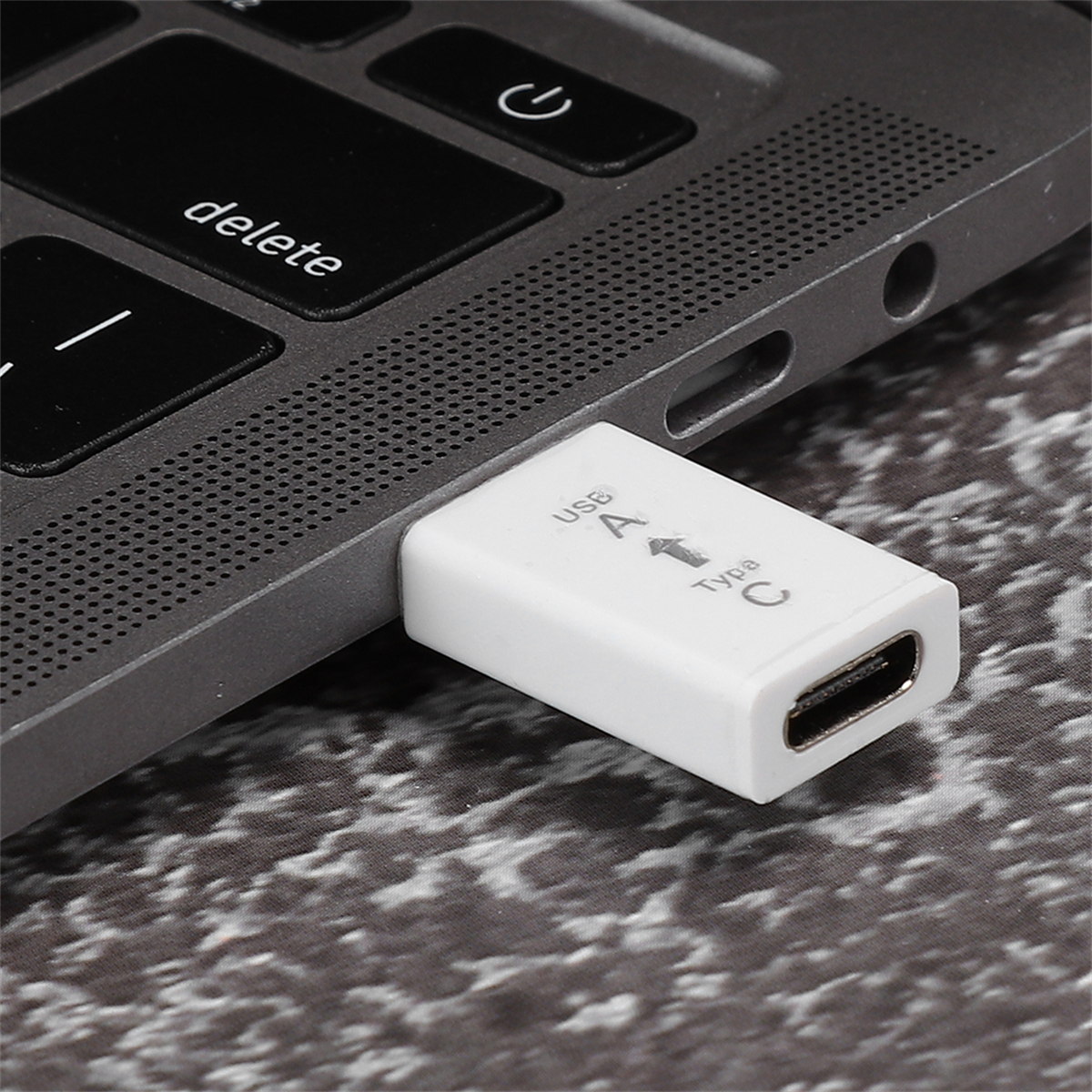 Weißer USB-C-Adapter, der an einen Laptop angeschlossen ist. Er hat USB A- und Typ C-Beschriftungen.