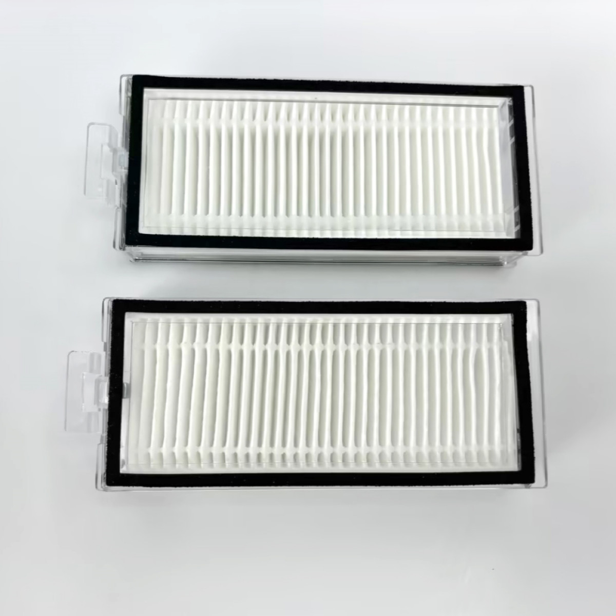 Dwa białe prostokątne filtry do odkurzacza z czarnymi ramkami leżą na białej powierzchni.