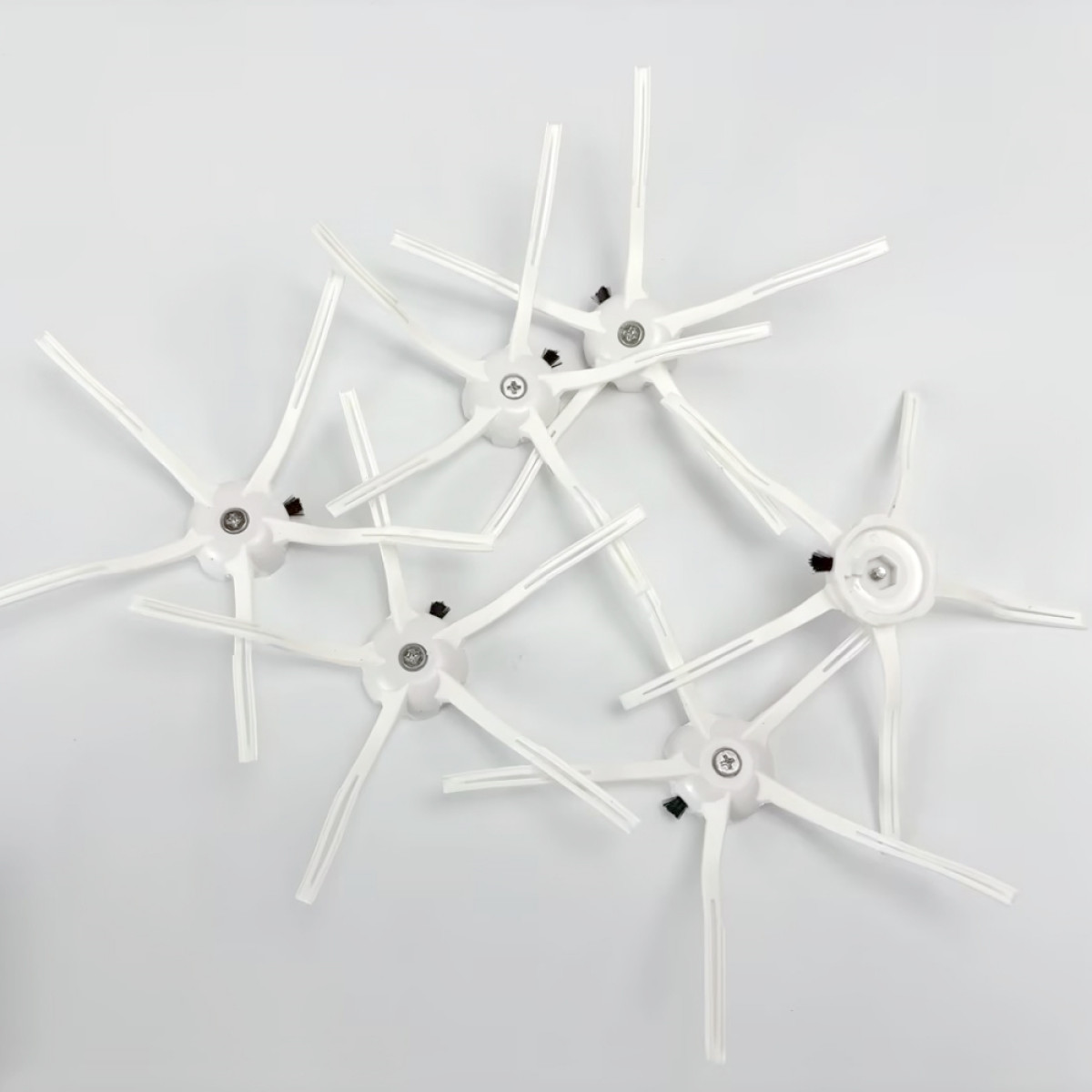 Pięć białych szczotek do robota sprzątającego. Mają kształt gwiazdy z włosiem.