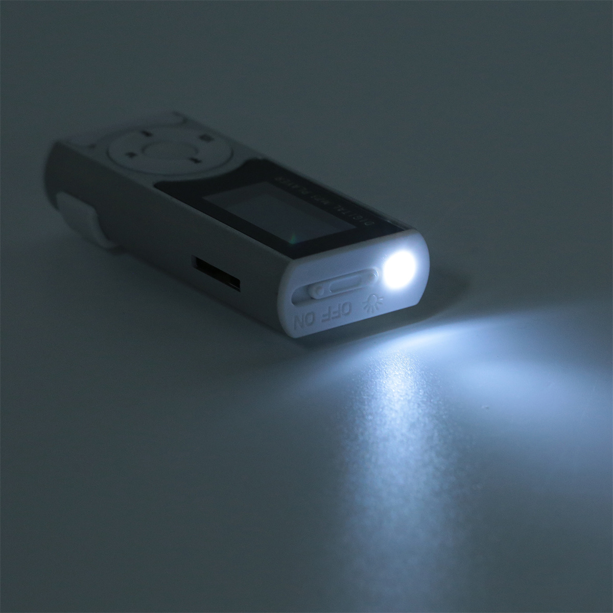 Ein kleiner grauer MP3-Player mit eingeschaltetem Licht, das die Oberfläche darunter beleuchtet.