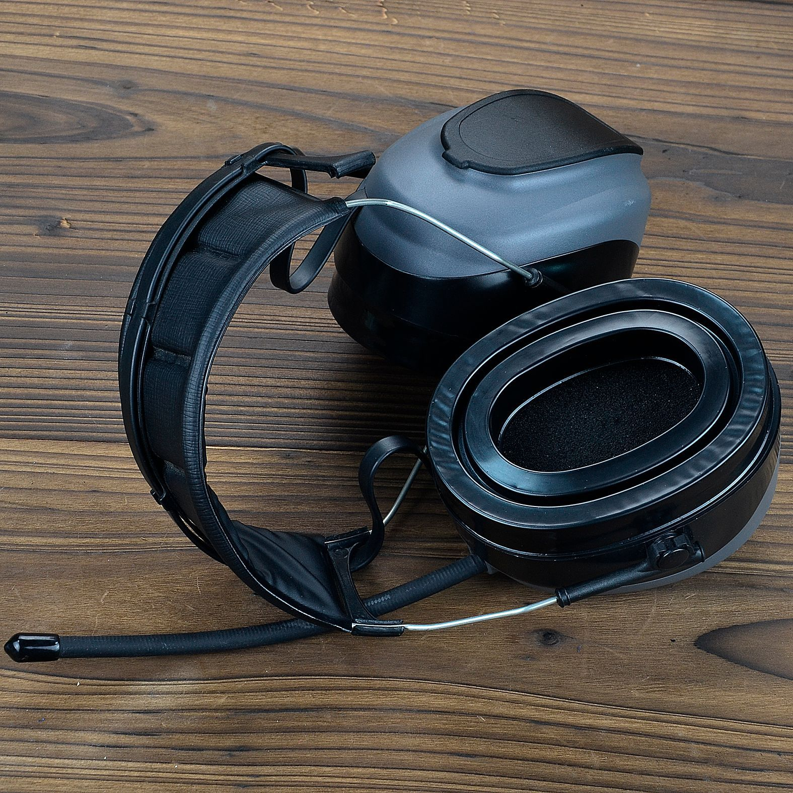 Czarne i szare słuchawki na drewnianej powierzchni.