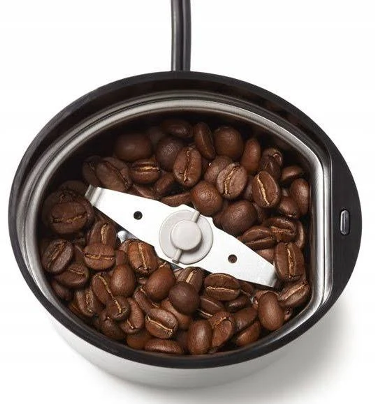 Młynek do kawy. Widok z góry, wypełniony ziarnami kawy. Ostrze na środku.