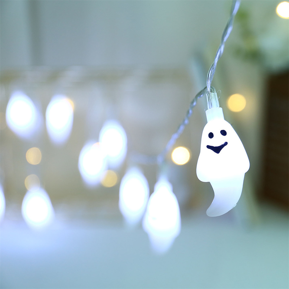 Lichterkette mit weißen Geisterlichtern auf unscharfem Hintergrund mit Bokeh-Effekt.