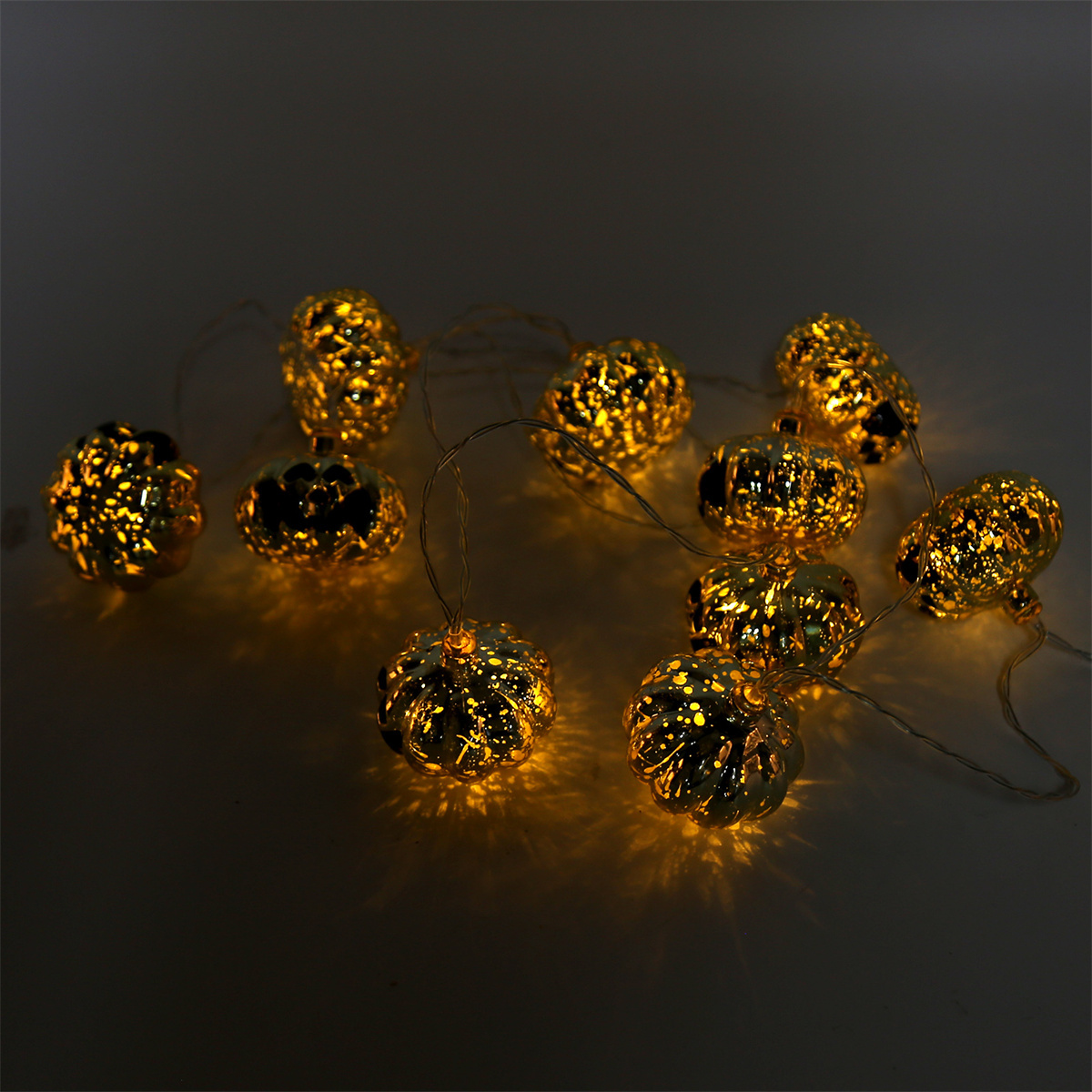 Lichterkette mit goldenen Kürbissen. Sie leuchten warm auf dunklem Hintergrund. Halloween-Dekoration.