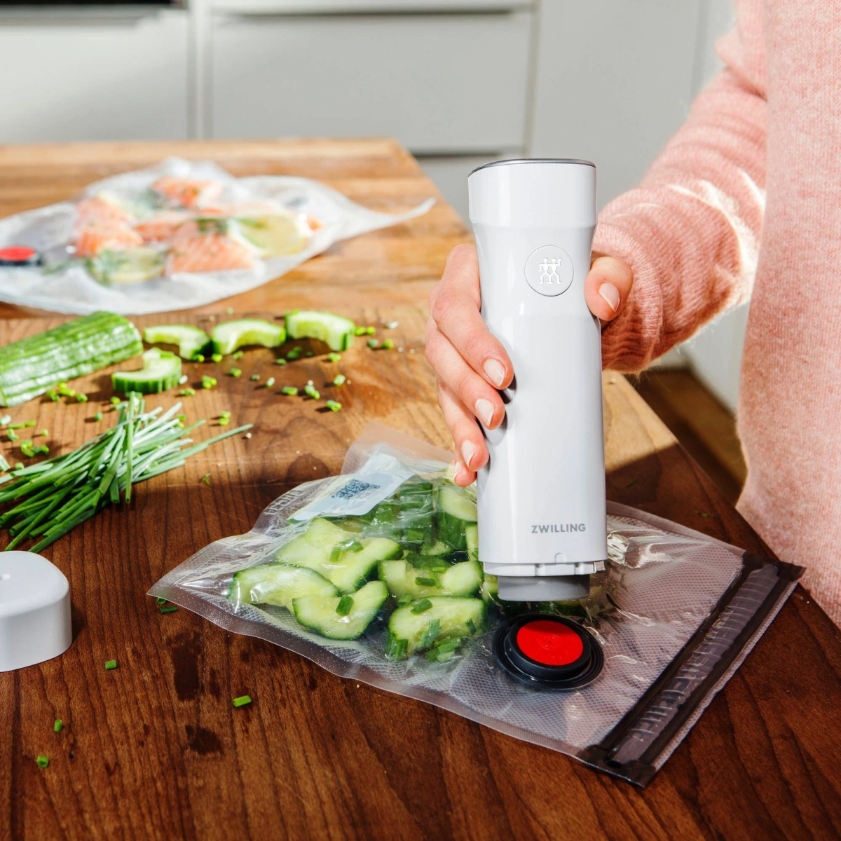 Osoba zgrzewająca próżniowo ogórki w worku za pomocą białej zgrzewarki próżniowej Zwilling.