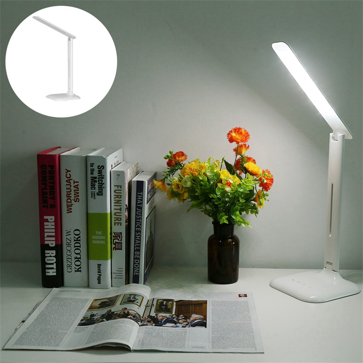 Eine weiße Schreibtischlampe auf einem Schreibtisch mit Büchern, Blumen und einer Zeitschrift.
