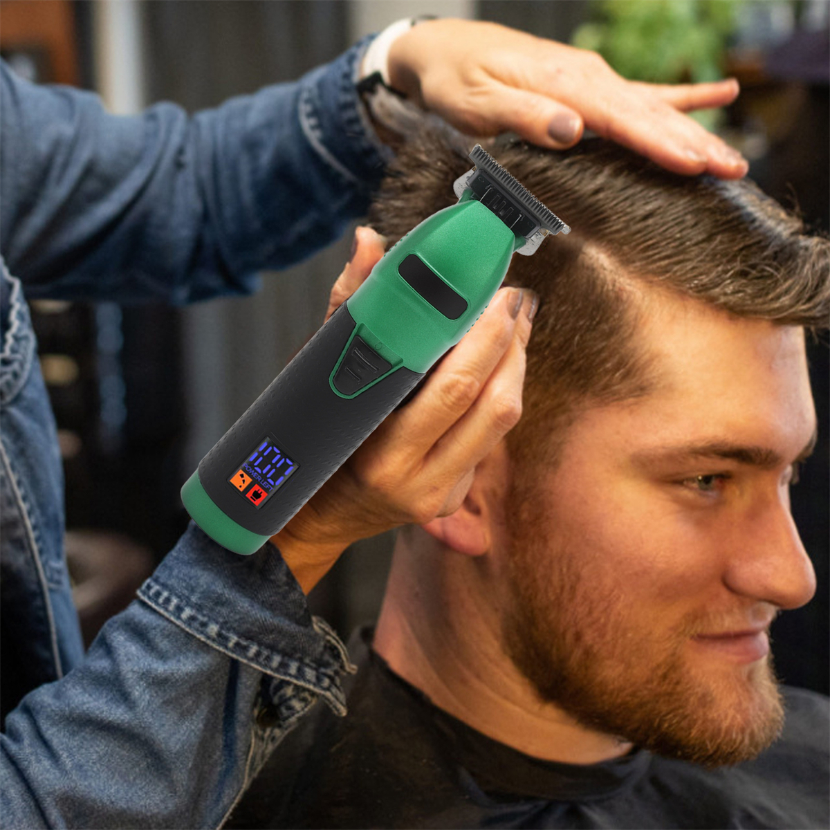 Ein Mann, dem mit einem grün-schwarzen elektrischen Trimmer von einer Hand die Haare geschnitten werden.