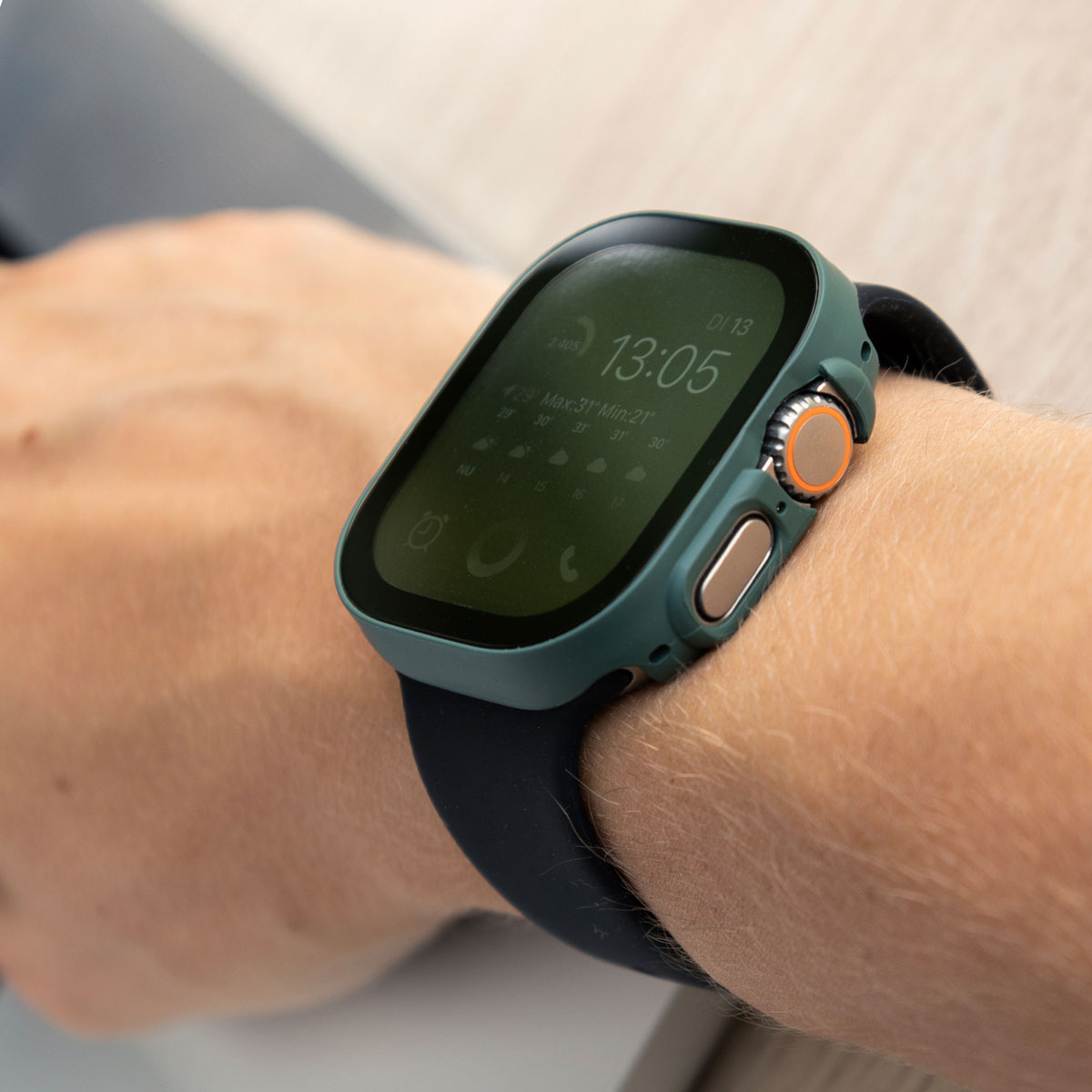 Apple Watch Ultra on wrist, with green case and black band. The watch displays the time and data.