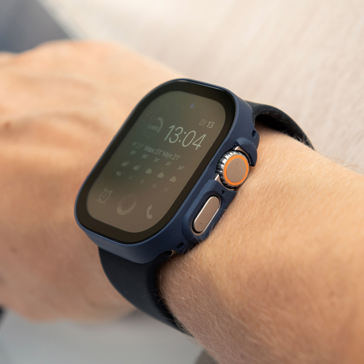A wrist with a watch, the watch has a blue case and an orange button.