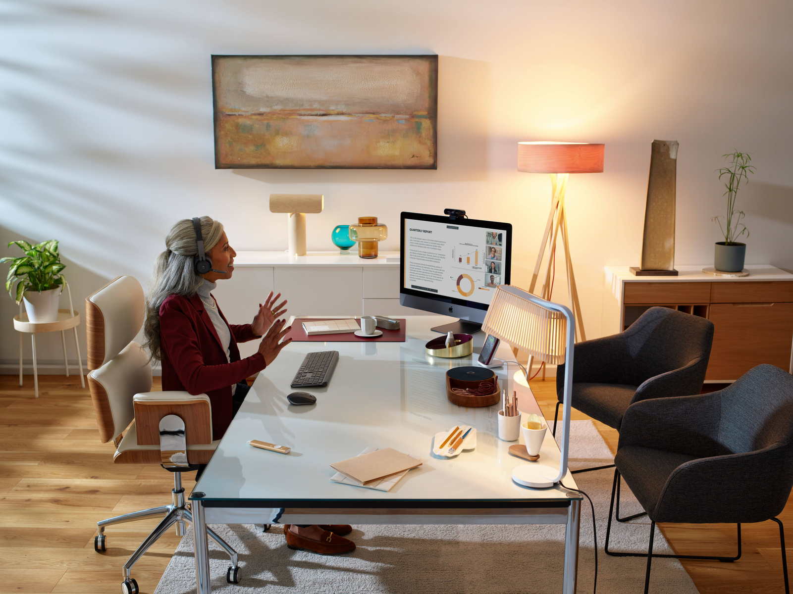 Kobieta podczas rozmowy wideo przy biurku z monitorem i lampą.