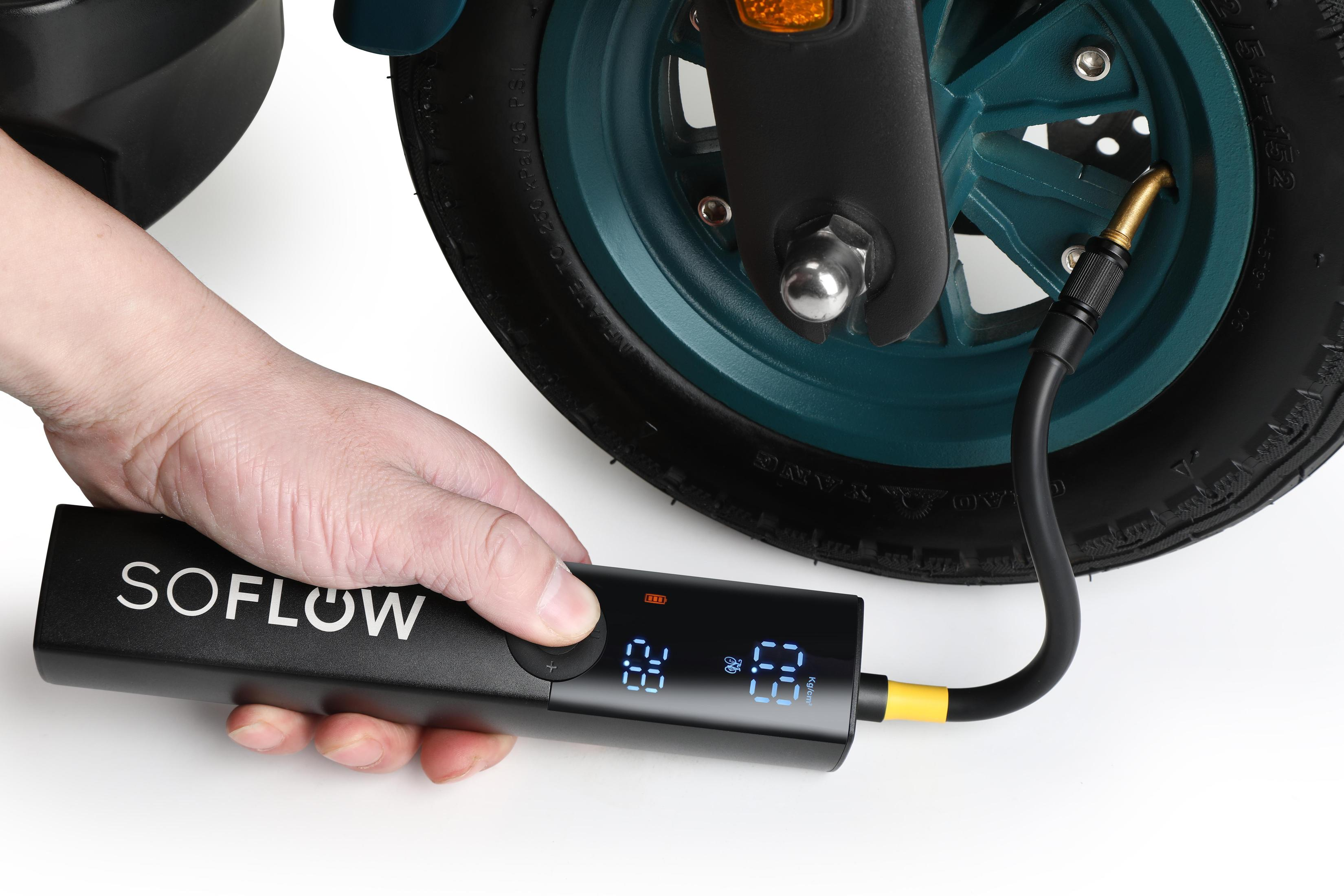 Une pompe à air SOFLOW noire gonflant un pneu, montrant l'affichage numérique et la connexion du tuyau.