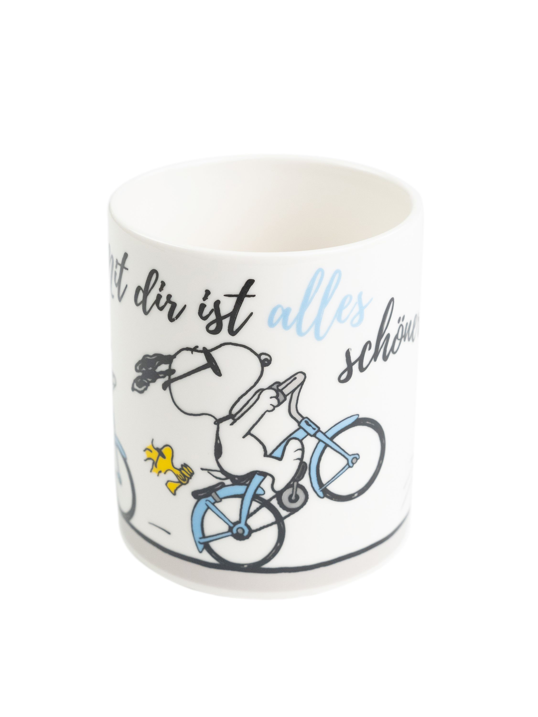 Eine weiße Tasse mit Snoopy-Cartoon, der Fahrrad fährt. Text ist vorhanden.