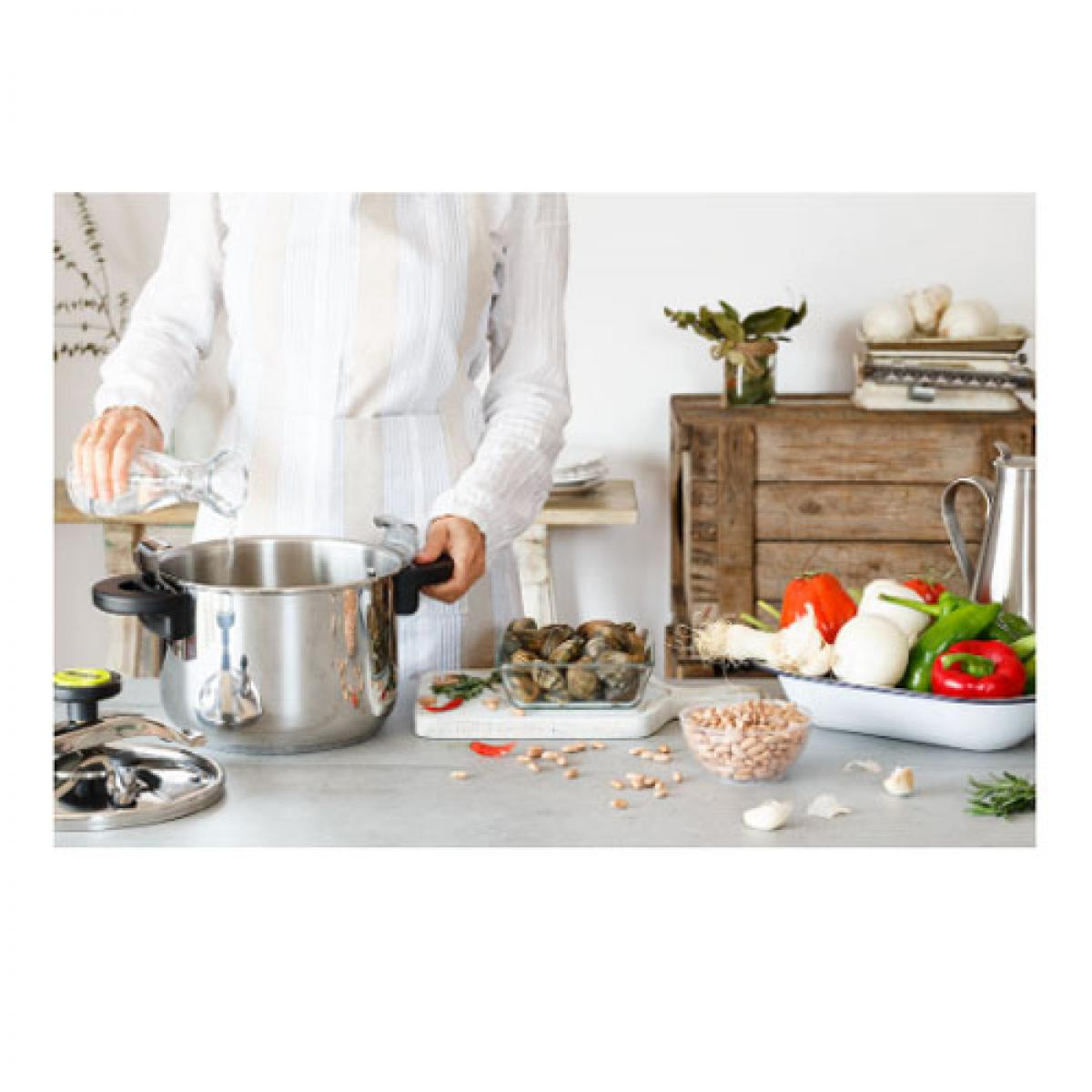 Persona añadiendo agua a una olla a presión. Ingredientes y verduras en la mesa.