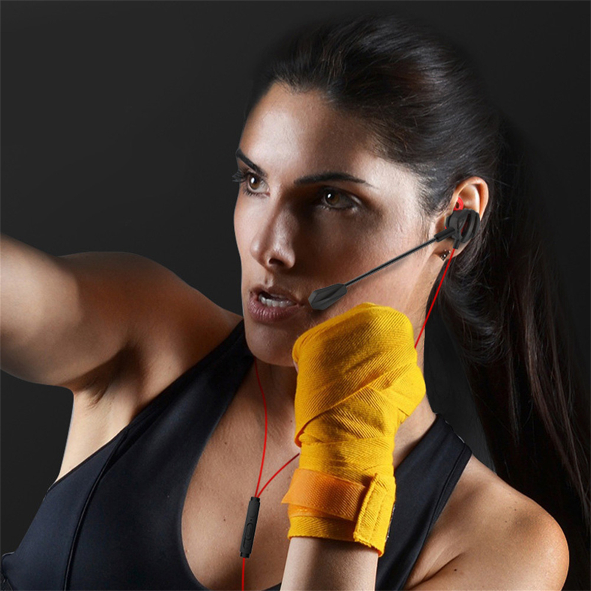 Eine Frau in einem schwarzen Oberteil mit Headset, gelbem Handgelenkband, konzentriert.