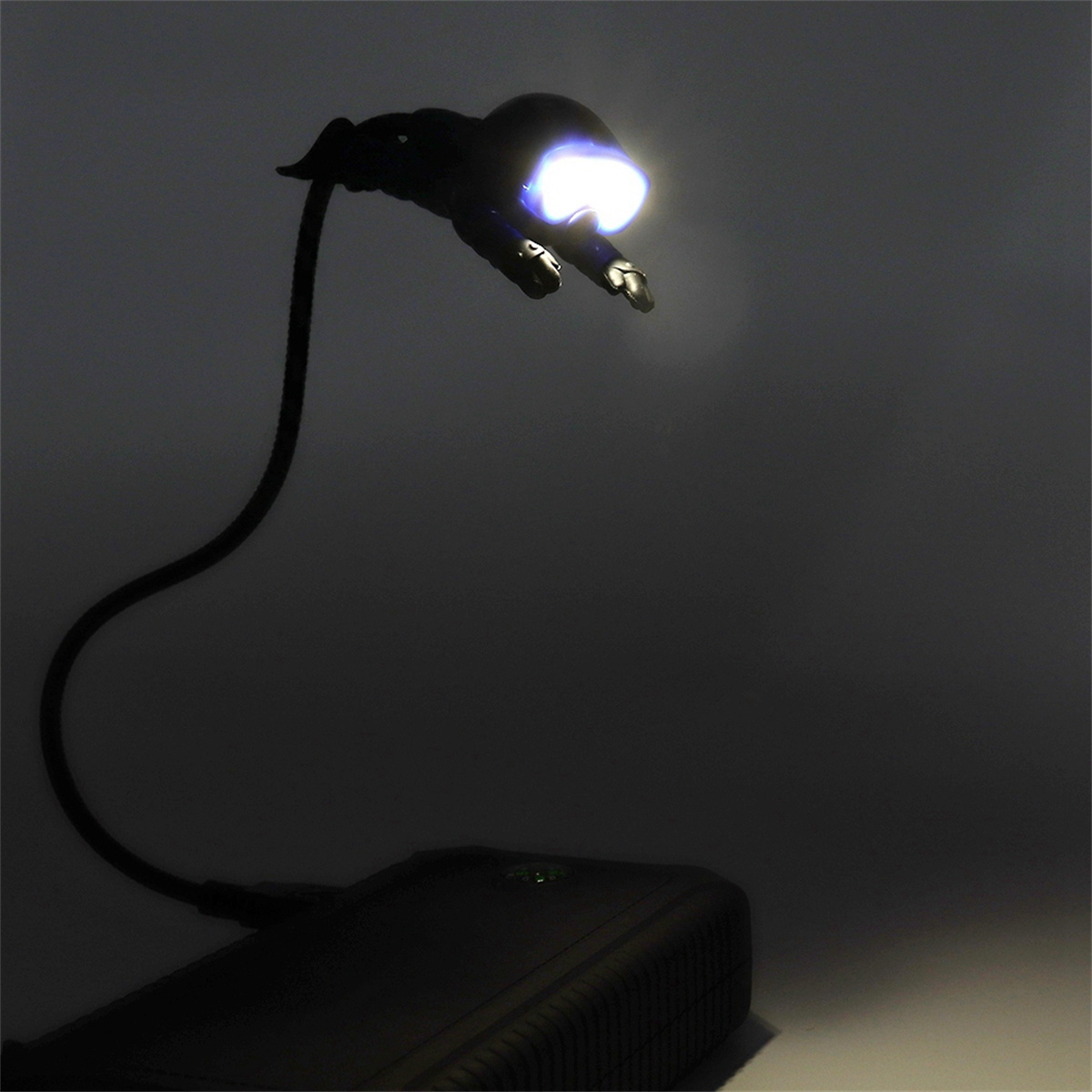 Schwarze Schreibtischlampe mit flexiblem Hals, die helles Licht aussendet. Dunkler Hintergrund.