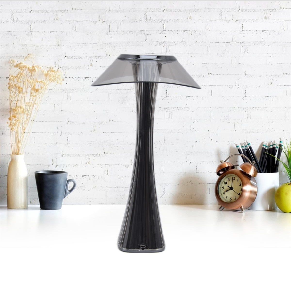 Moderne schwarze Tischlampe mit grauem Schirm auf einem weißen Schreibtisch.
