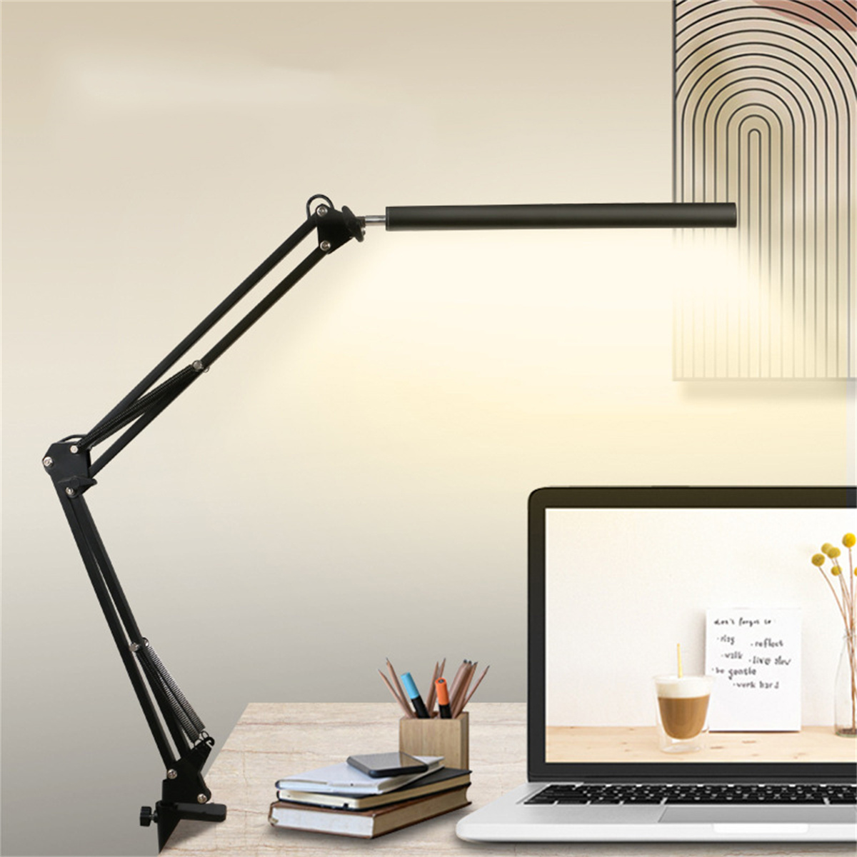 Schwarze Schreibtischlampe, über einen Schreibtisch mit Laptop, Notizbüchern und Bleistiften.