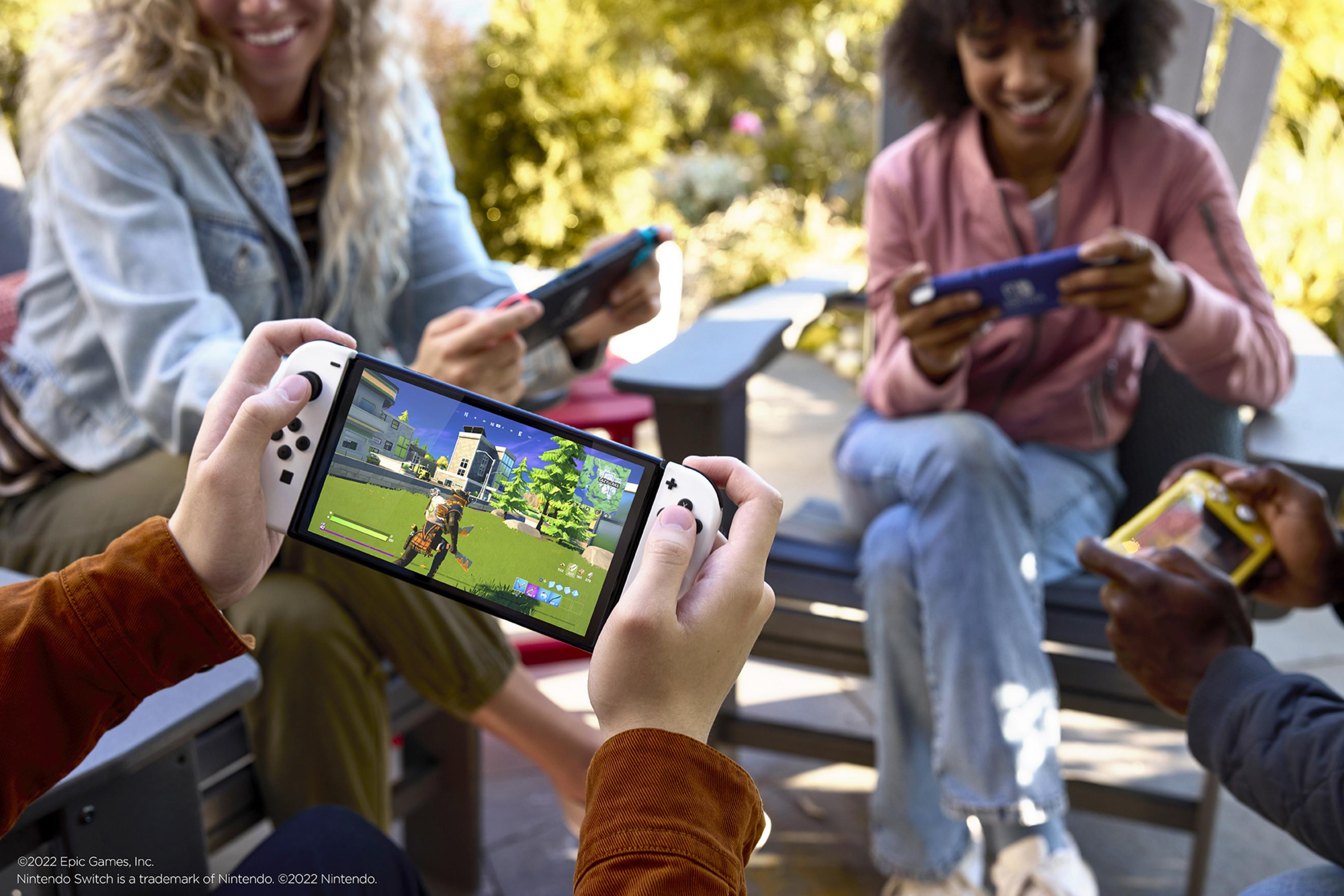 Un gruppo di persone gioca ai videogiochi su diversi dispositivi all'aperto.