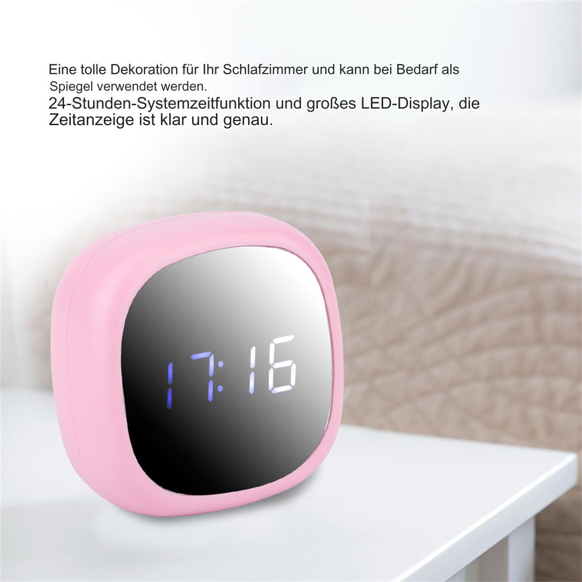 Rosa Wecker mit der Anzeige 17:16. Er steht auf einer weißen Oberfläche mit einem Bett im unscharfen Hintergrund.