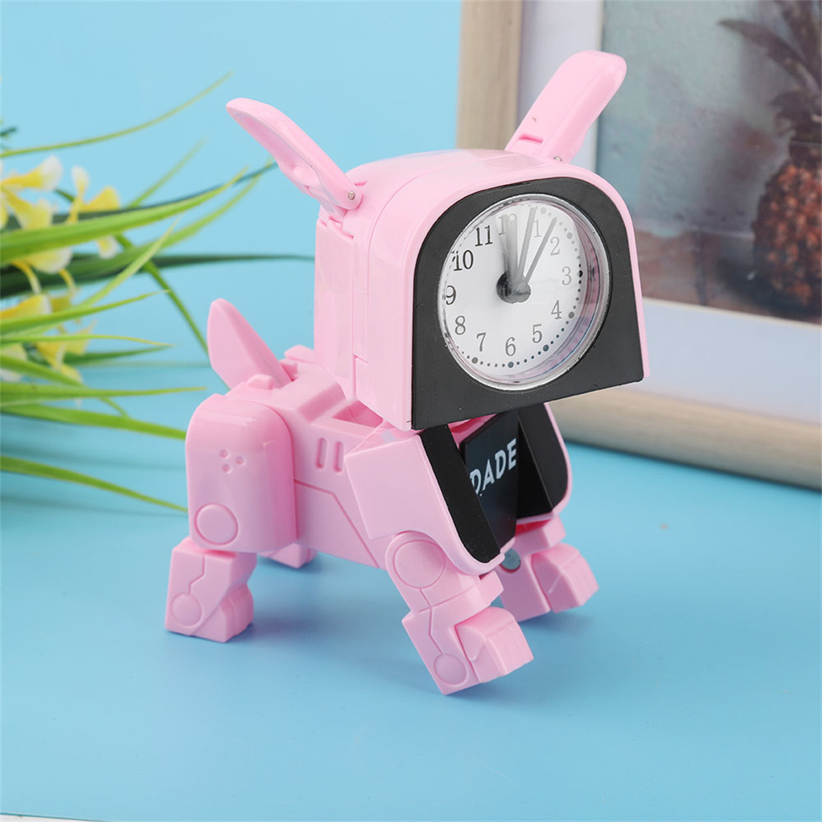 Rosa Spielzeug-Roboterhund mit Ziffernblatt, steht auf blauer Oberfläche.