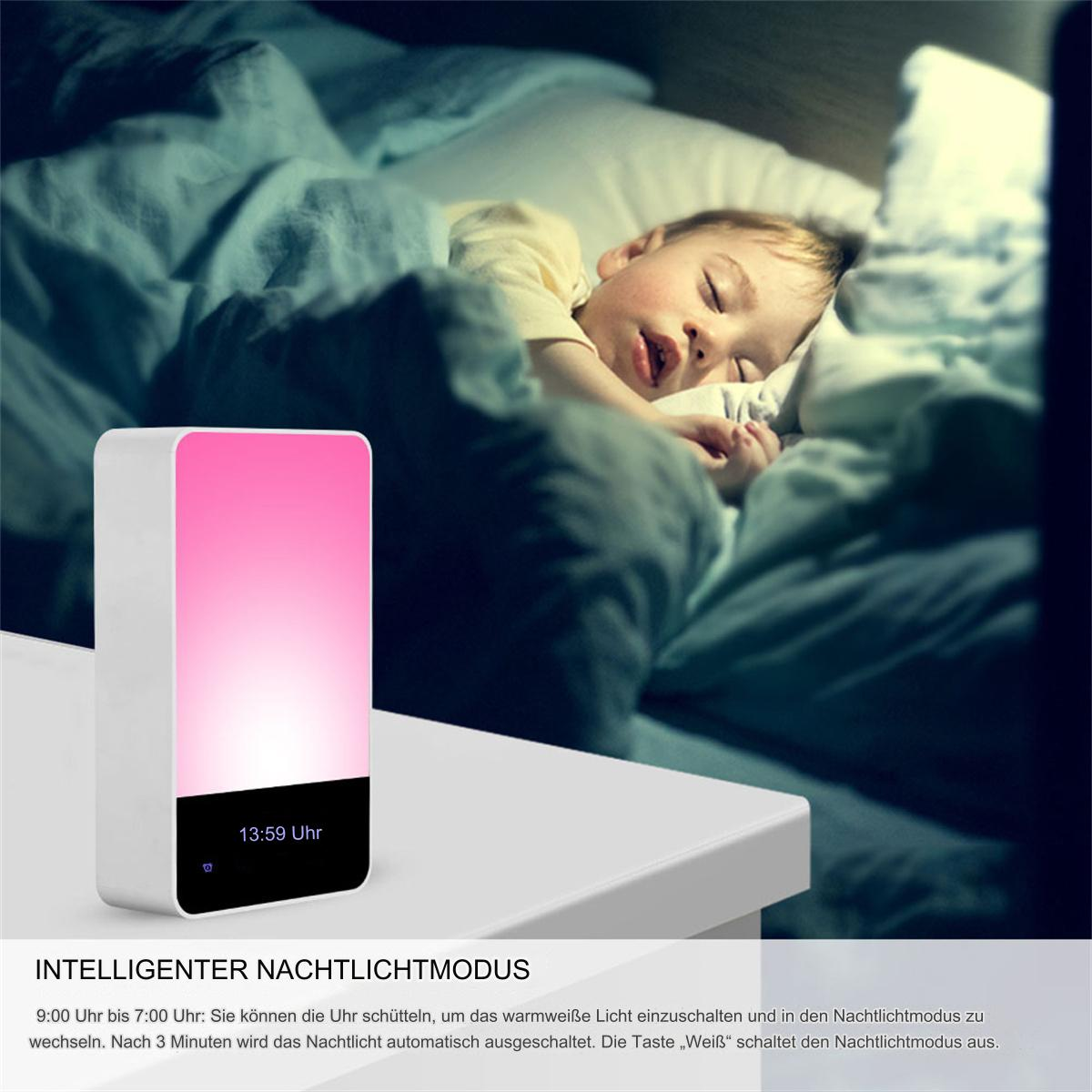Kind schläft neben einem rosa Lichtwecker auf einem weißen Tisch.