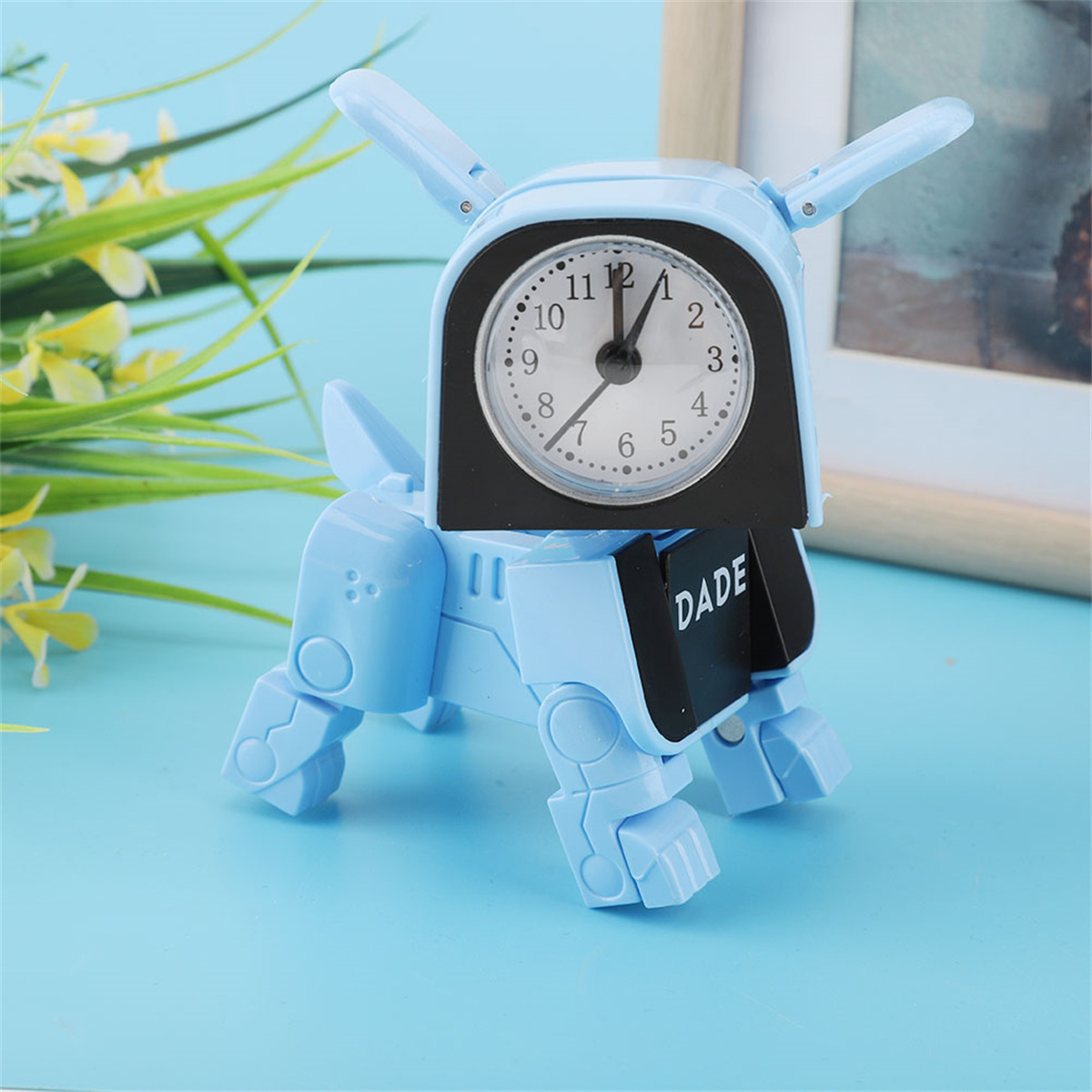 Blaue Roboter-Hund-Uhr. Sie hat ein Zifferblatt und Ohren und steht auf einer blauen Oberfläche. Ein Bild im Hintergrund.