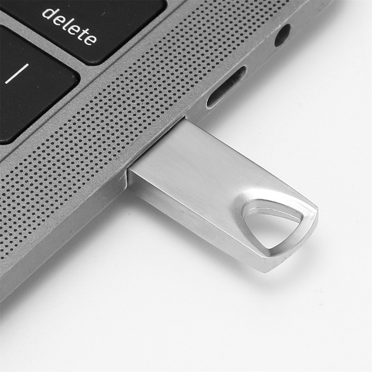 Silberner USB-Stick, der in einen Laptop gesteckt ist. Die Entf-Taste ist sichtbar. Weißer Hintergrund.