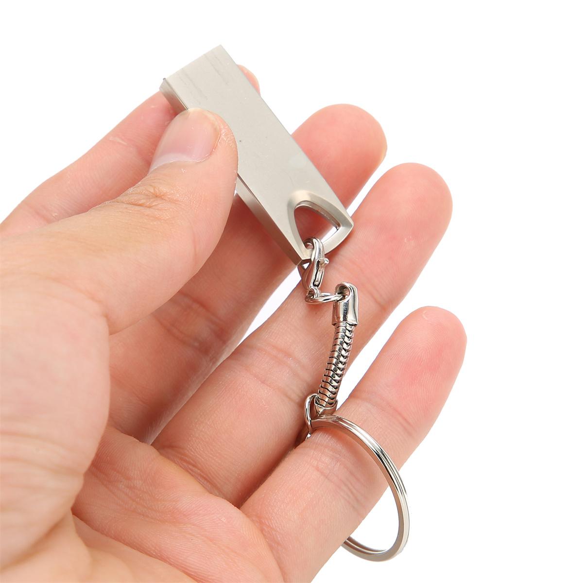 Eine Hand, die einen silbernen USB-Stick mit einem kleinen Schlüsselanhänger hält. Weißer Hintergrund.