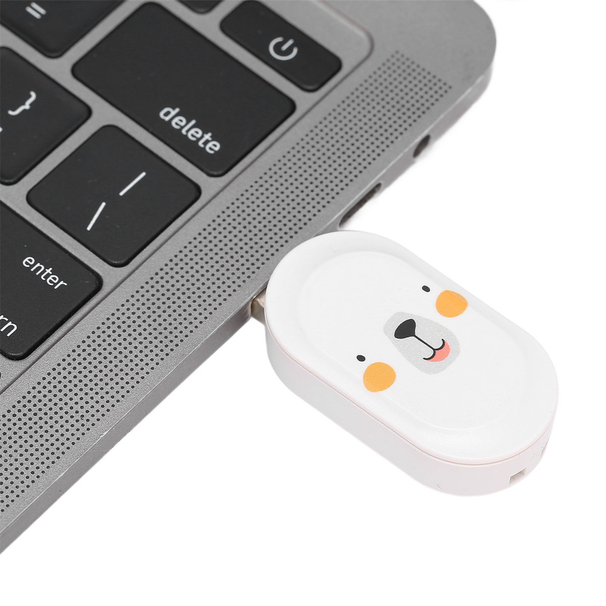 Ein weißer USB-Stick in Form eines Bärenkopfes ist an einen Laptop angeschlossen.