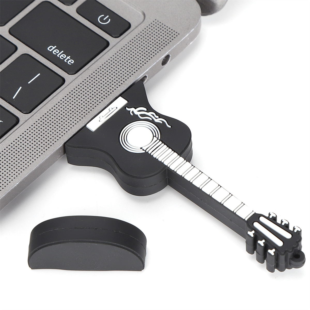 Schwarzer USB-Stick in Gitarrenform, der in einen Laptop gesteckt ist. Daneben eine schwarze Kappe.