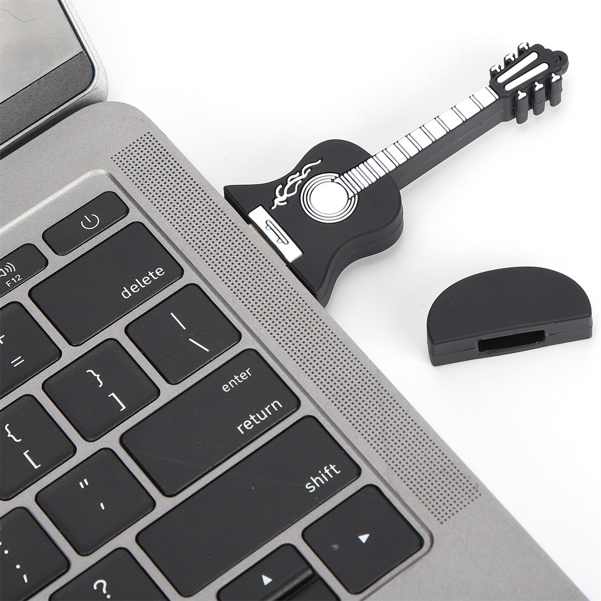 Ein schwarzer USB-Stick in Gitarrenform, der in einen Laptop eingesteckt ist. Weißer Hintergrund.