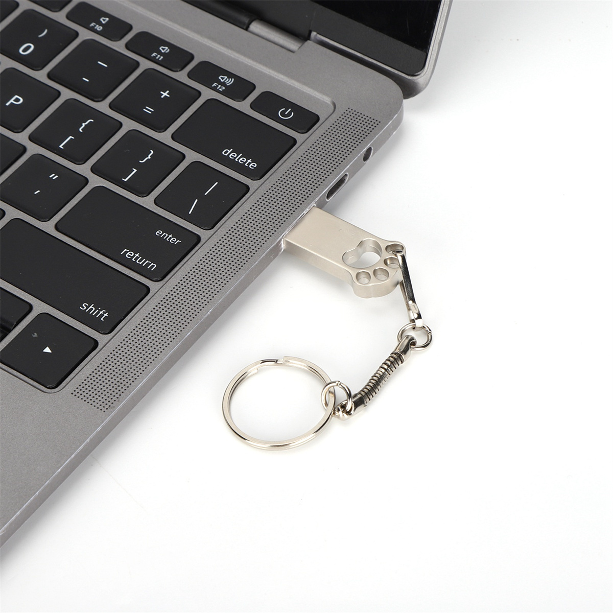 Ein silberner USB-Stick, der in einen Laptop gesteckt ist. Der Stick hat einen Schlüsselring und ein pfotenförmiges Design.