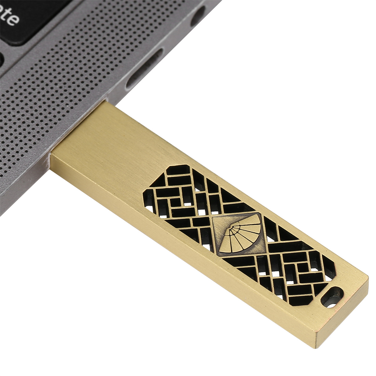 Goldfarbener USB-Stick, der in einen Laptop gesteckt ist. Der Stick hat ein dekoratives Muster.