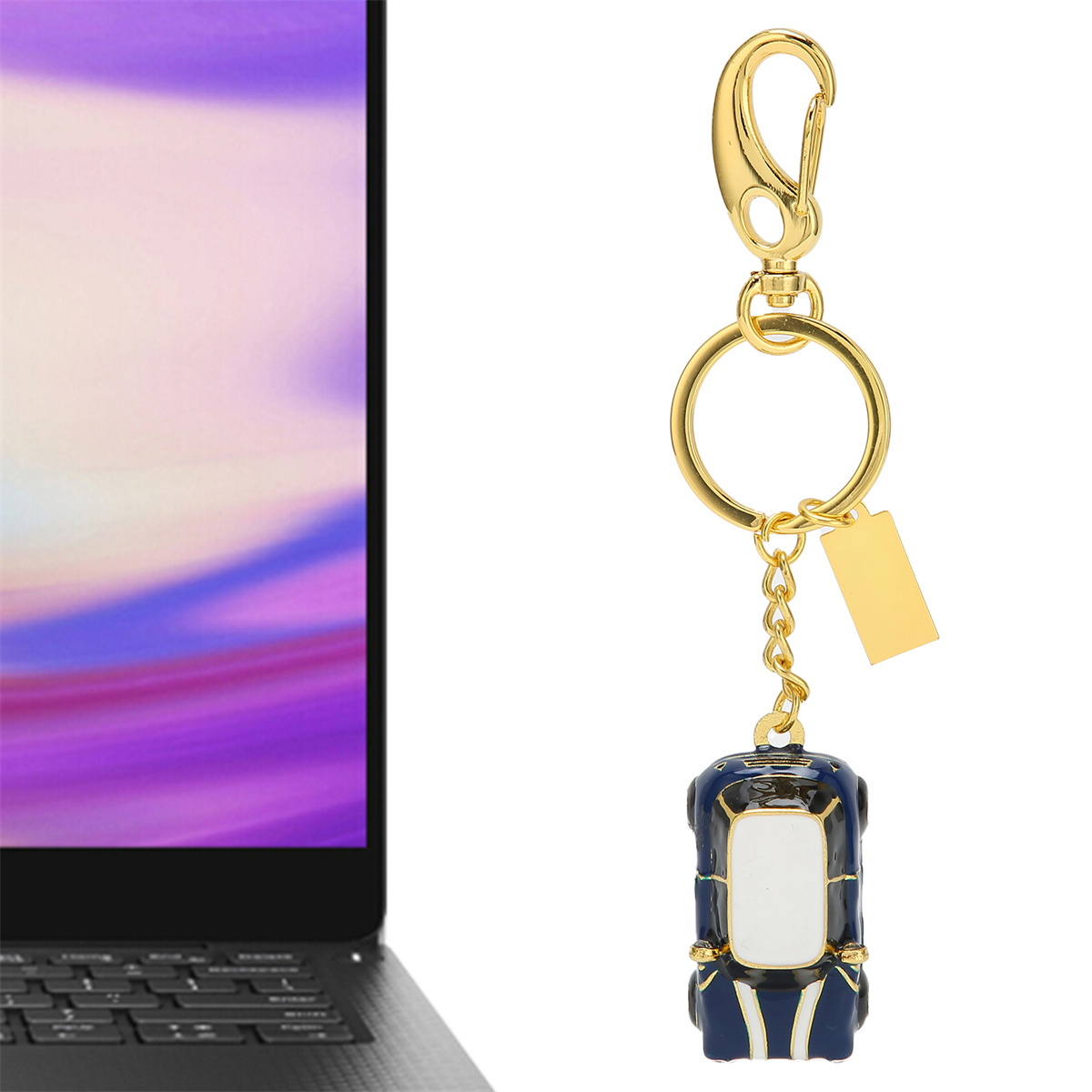 Ein goldener Schlüsselanhänger mit einem blau-weißen Autoanhänger neben einem Laptop.
