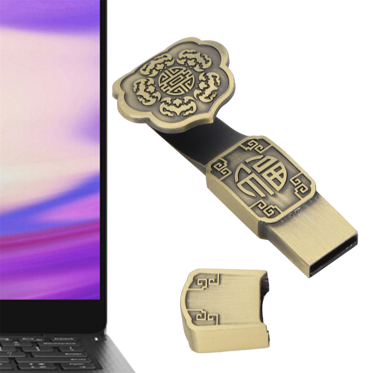 Ein goldener USB-Stick mit Verzierungen und abgenommener Kappe vor weißem Hintergrund. Laptop in der Ecke.