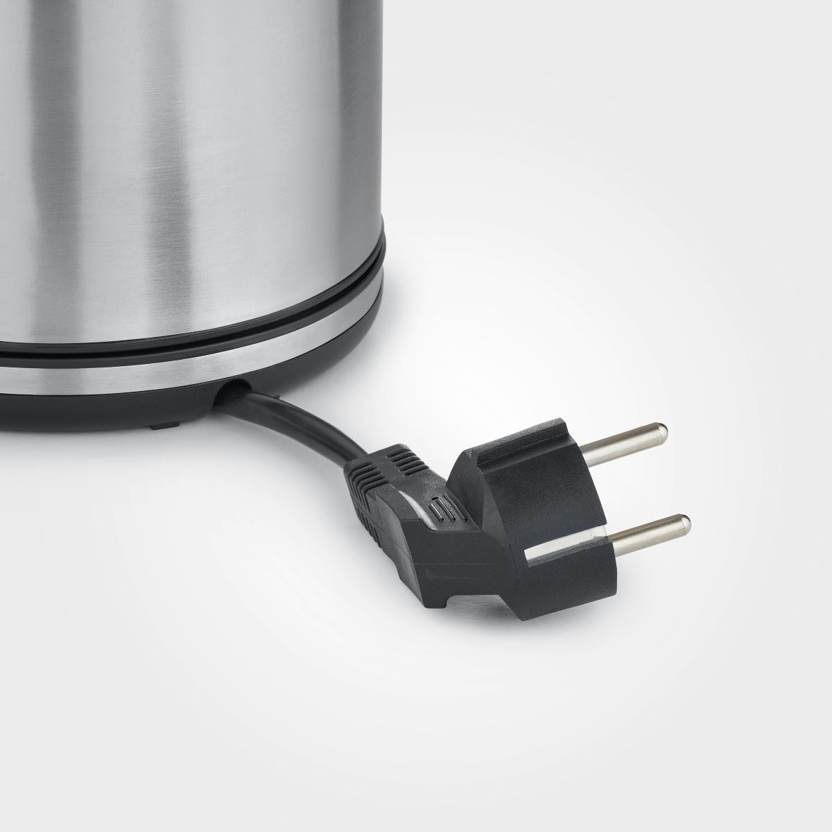 Wtyczka czajnika elektrycznego. Czarna wtyczka i przewód, czajnik ze stali nierdzewnej, białe tło.