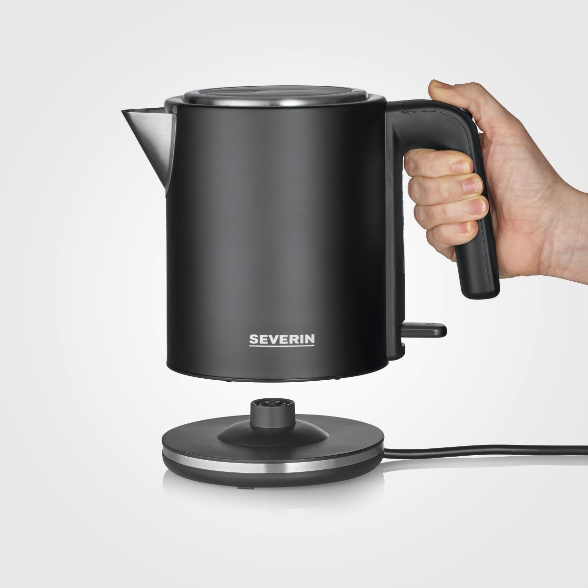 Un bollitore elettrico nero tenuto da una mano, che mostra il bollitore e la sua base, con un cavo nero.