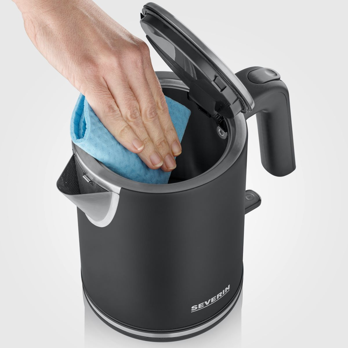 Una mano pulisce l'interno di un bollitore nero con un panno blu.