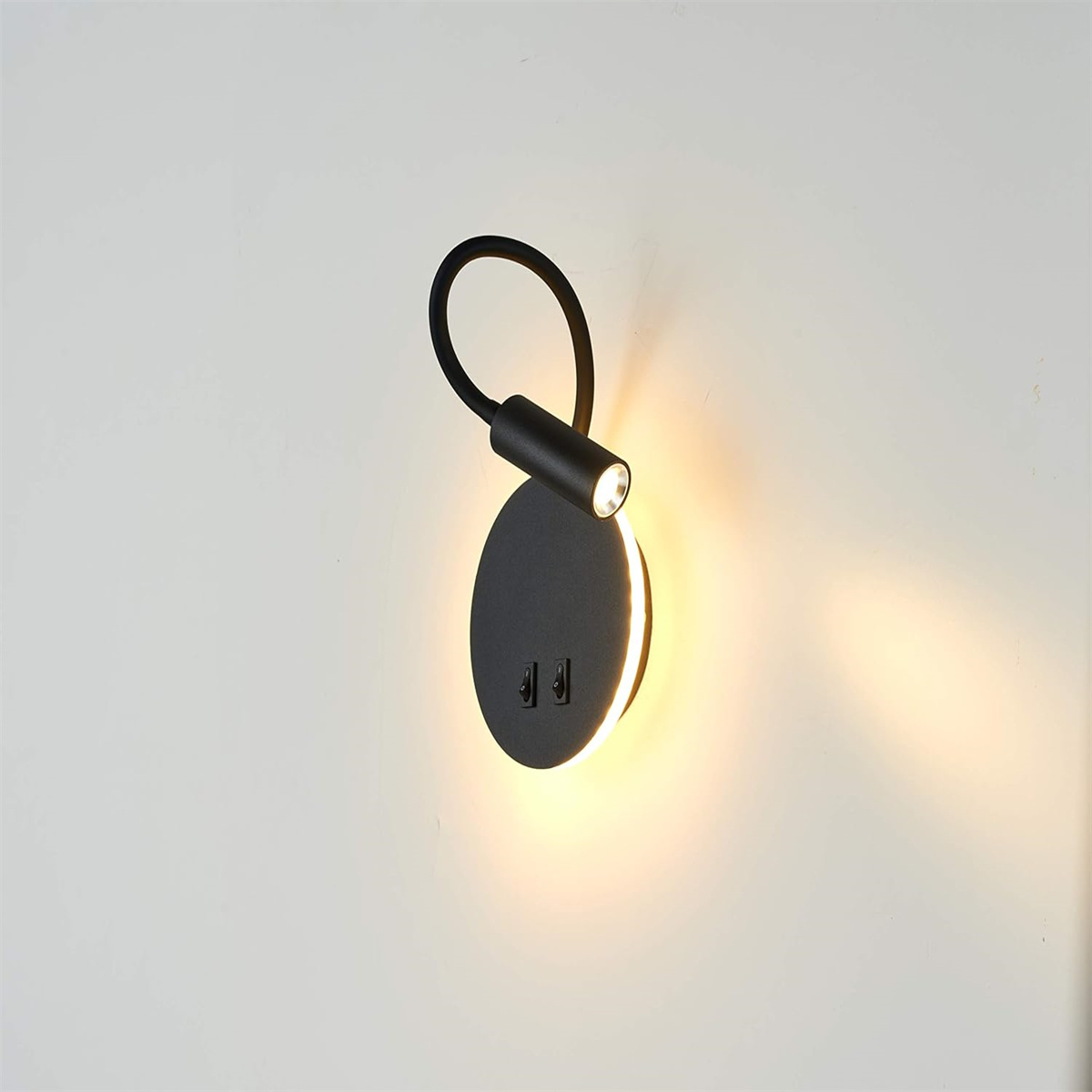 Schwarze moderne Wandleuchte. Sie hat ein kreisförmiges Design und gibt warmes Licht ab.