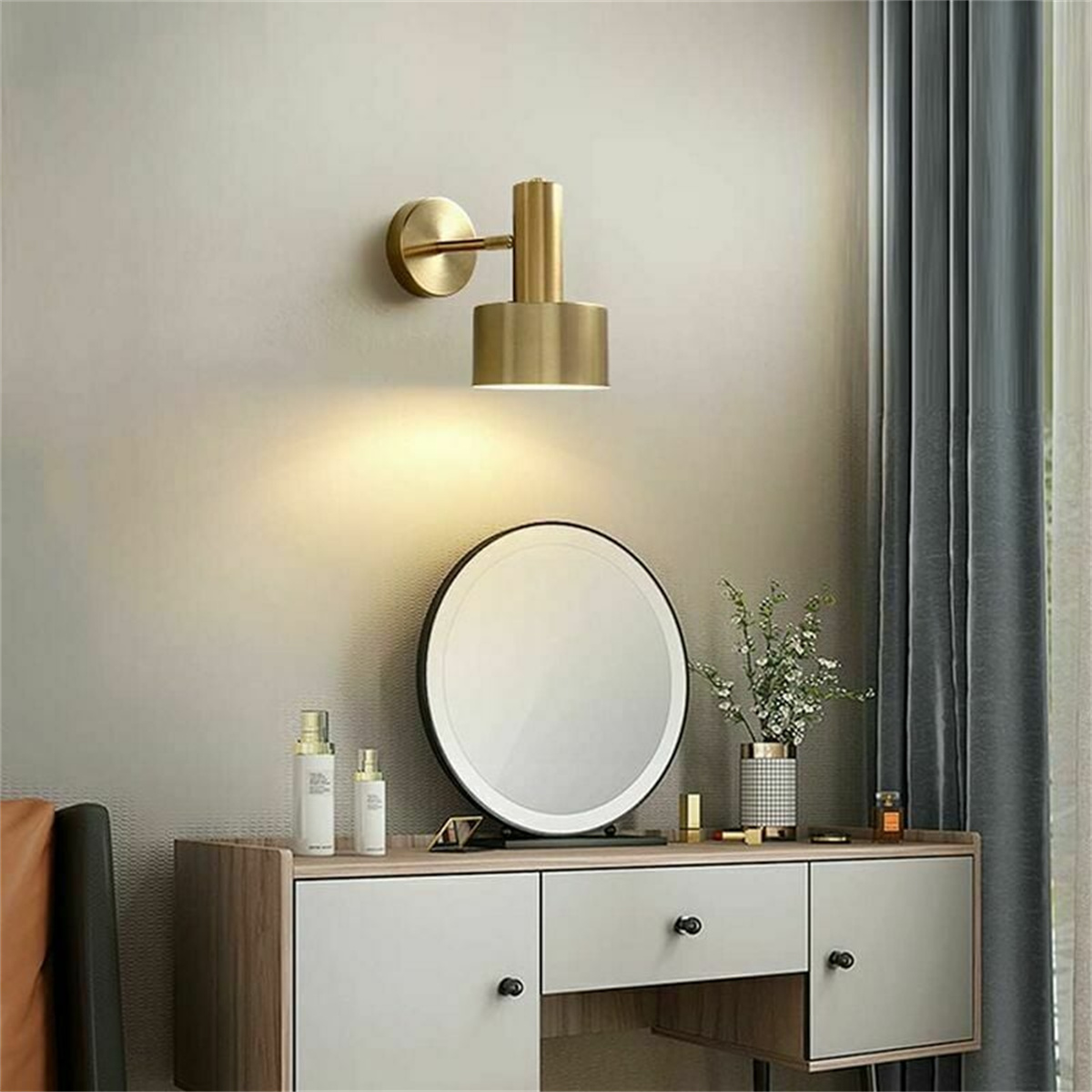 Eine goldene Wandlampe scheint auf einen weißen Schminktisch mit Spiegel und Kosmetik.