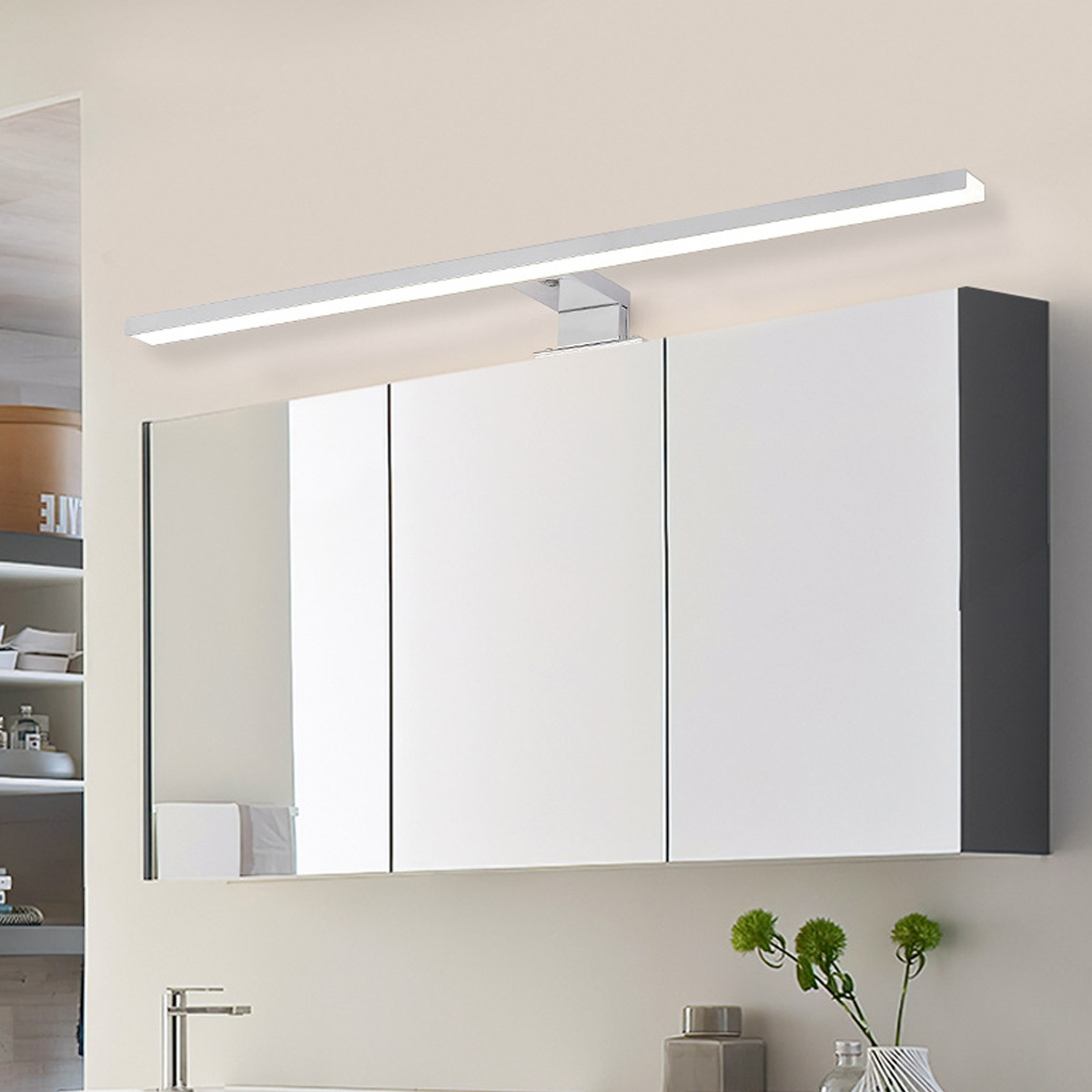 Badspiegel mit LED-Licht darüber. Drei Spiegeltüren und ein silberner Wasserhahn.