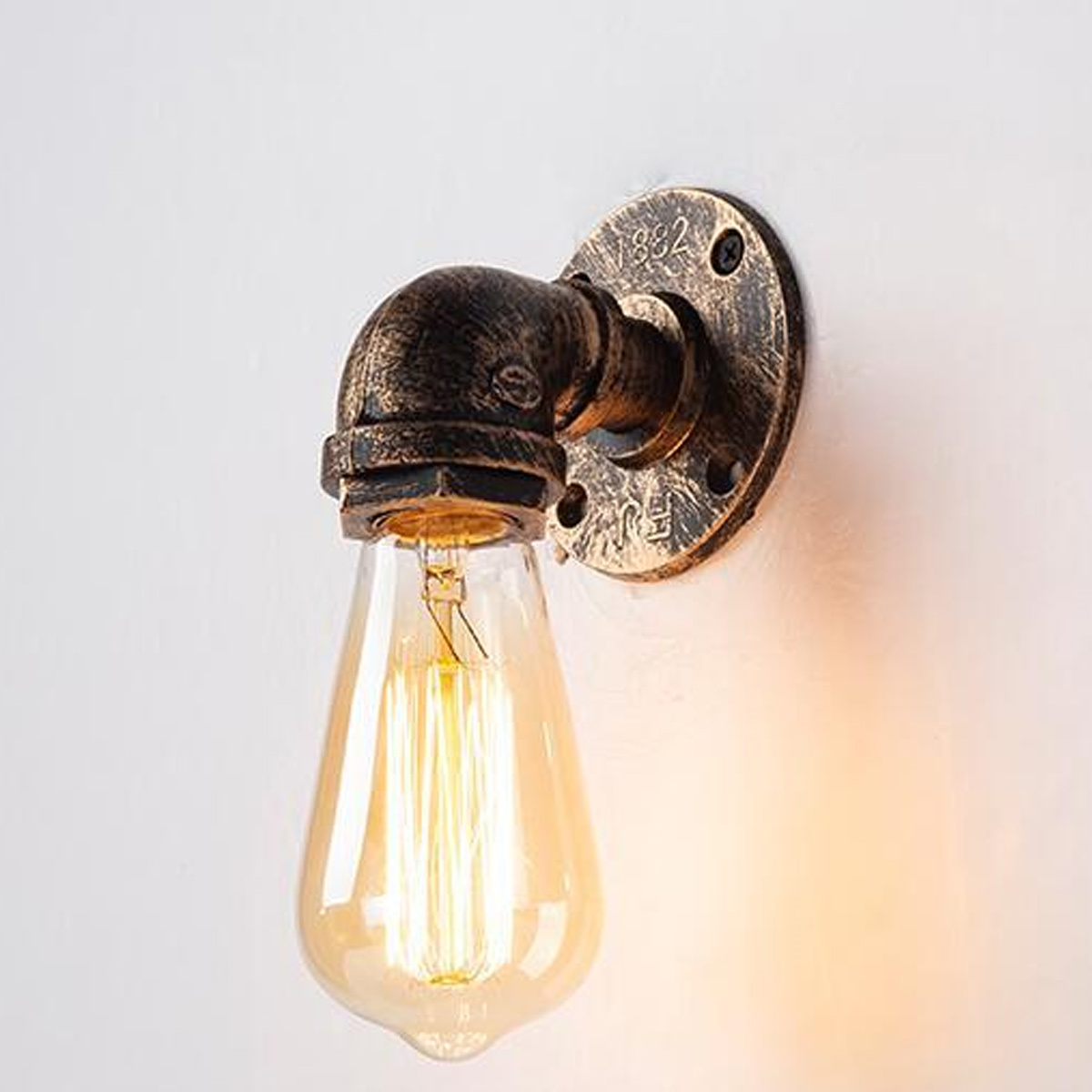 Edison-Glühbirne in einer Wandleuchte im Industriestil. Die Lampe ist an einer weißen Wand montiert.